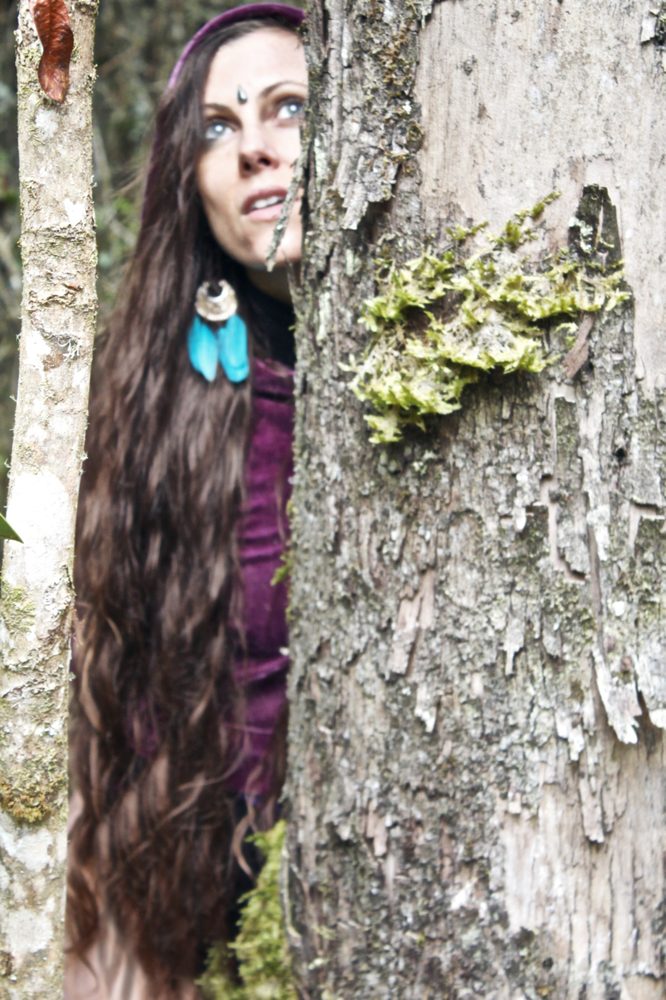 Michela peeking from behind a tree trunk — Walk with the Elf
