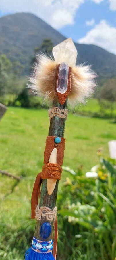 A handmade wand, crystal and tooth, held to the mountains